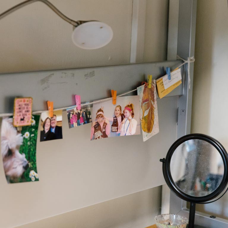 Close up of the corner of a dorm room where a student has a string of photos hanging