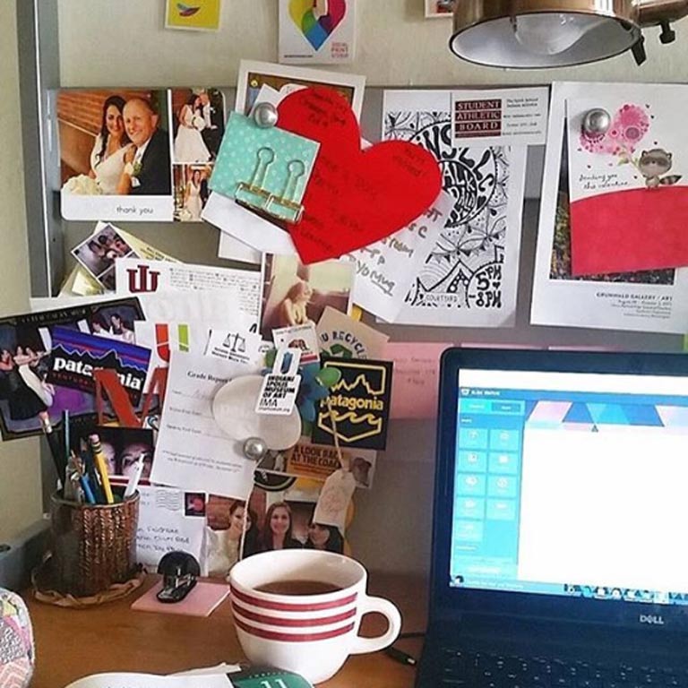 Close up of a student's desk cluttered with work, supplies, pictures, and various other items