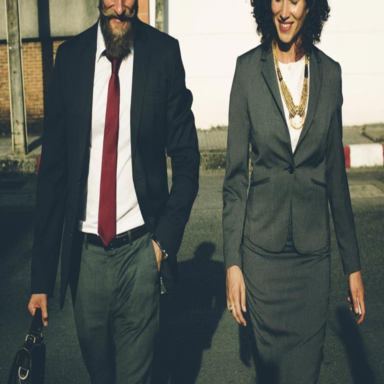 A man and a woman, both wearing suits, walk side-by-side