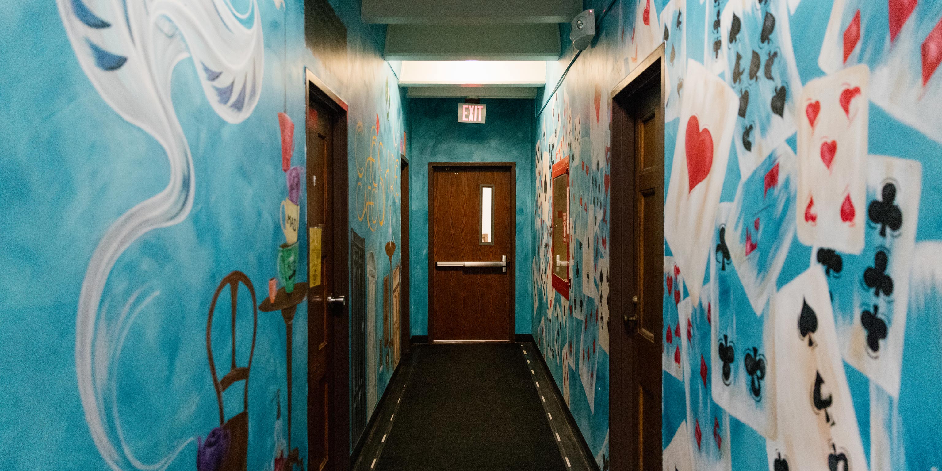Blue hallway covered with murals of playing cards and other Alice in Wonderland imagery