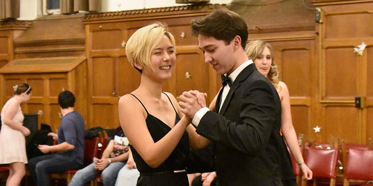 Student couple in formal attire dancing and laughing 