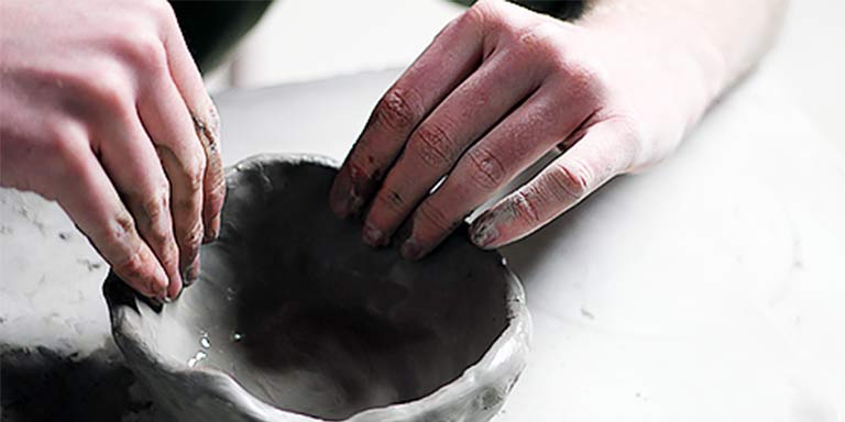 Two hands creating pottery